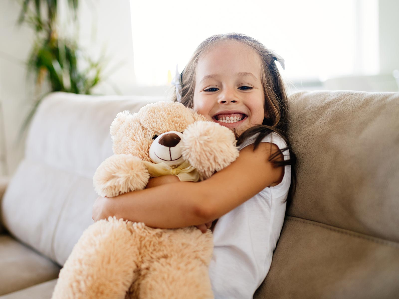 Happy girl cuddles stuffed bear